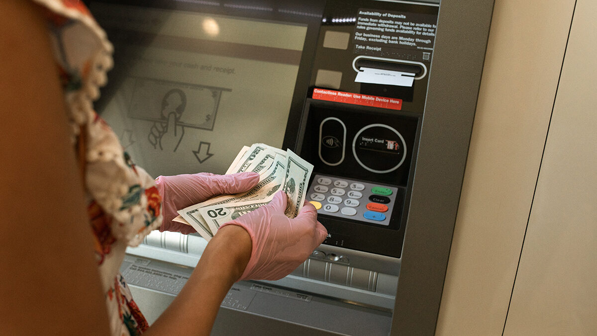 mulher contando dinheiro na frente de um caixa eletrônico